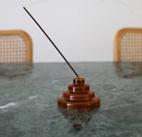 The Amber Glass Meso Incense Holder on a green marble surface. 