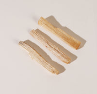 Three Palo Santo sticks on a creamish background. 