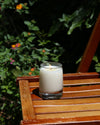 Yield 8oz Candle on an outdoor wooden shelf.