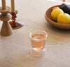 The 6 oz Clear Double Wall Glass filled with Juice on a wooden background. 