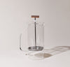 A Clear Glass French Press on a gray background.