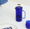 A Cobalt Glass French Press with a Cobalt Century Glass next to it on a white background. 