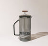 A Gray Glass French Press on a cream background.