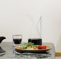 The Clear Pour Over Carafe and Clear Double Wall Glass filled with coffee on a grayish background. 